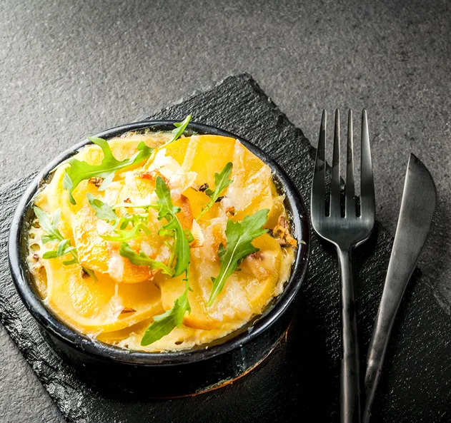 Gratin de pommes de terre dans un bol noir avec fourchette