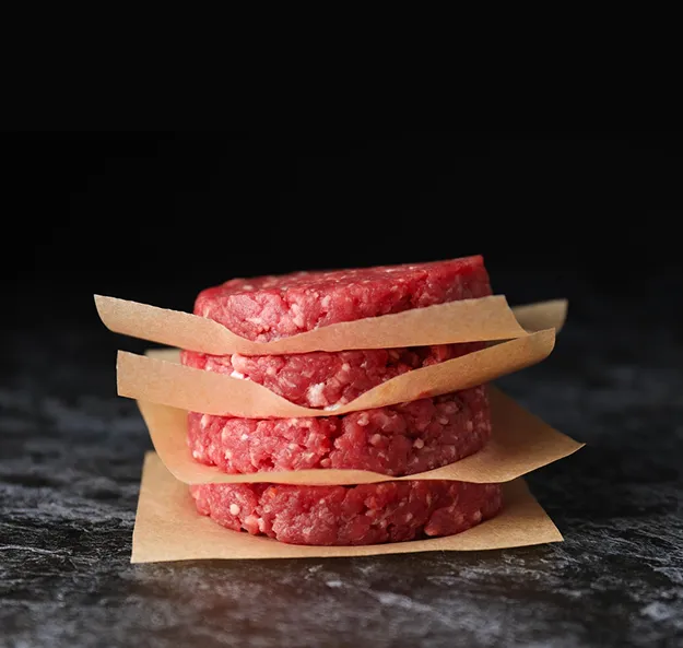 Tranches de viande crue empilées sur papier sulfurisé